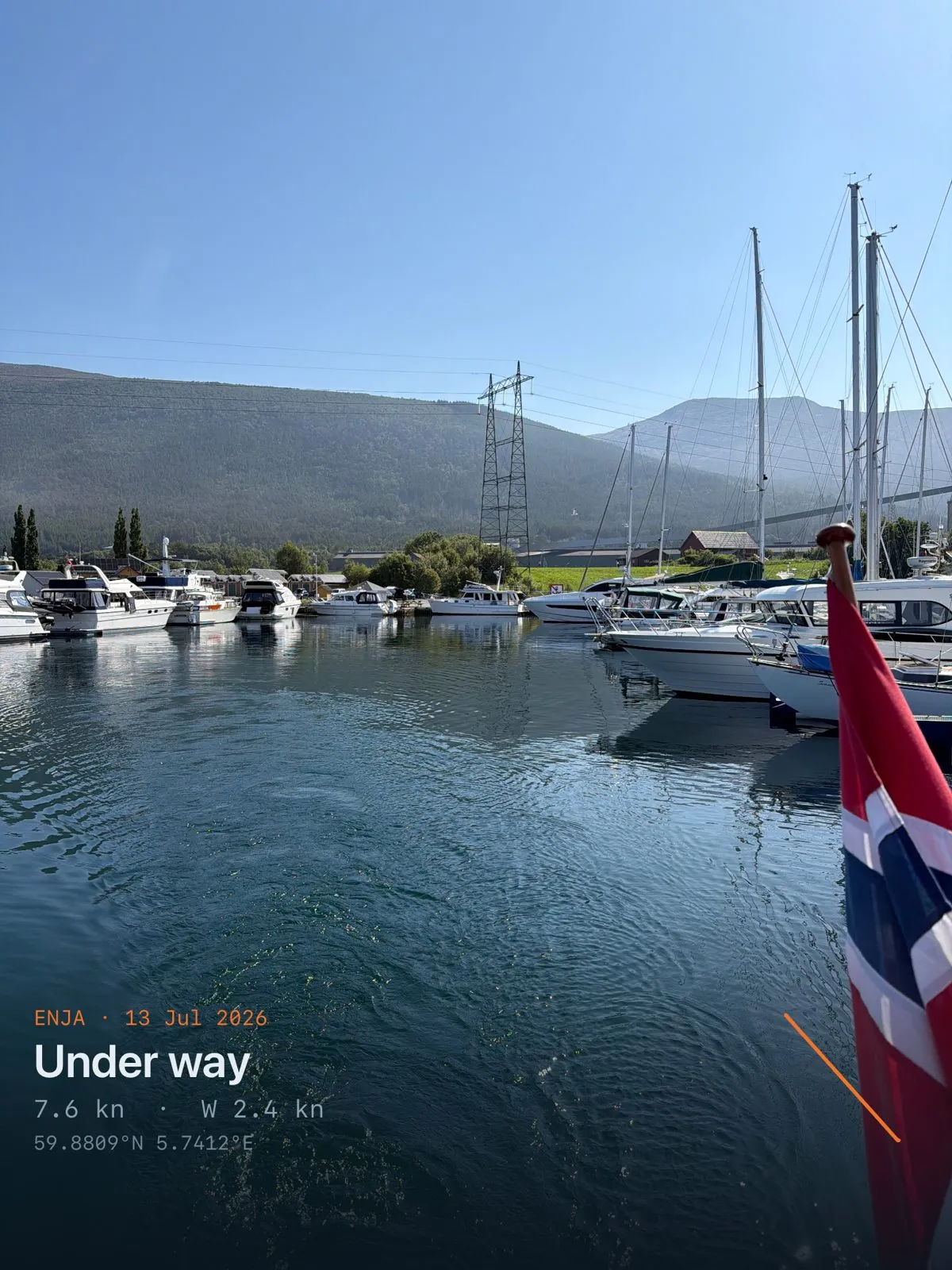 Boats moored in a small harbour below steep mountains in morning light