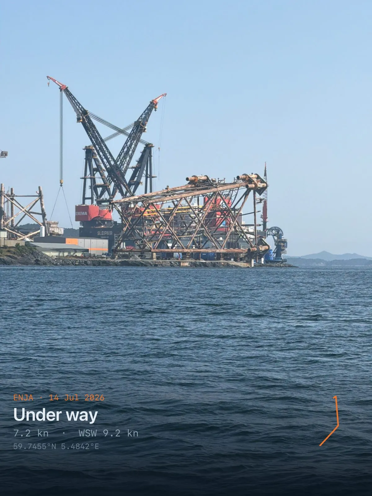 A large offshore construction crane at a shipyard under a clear sky
