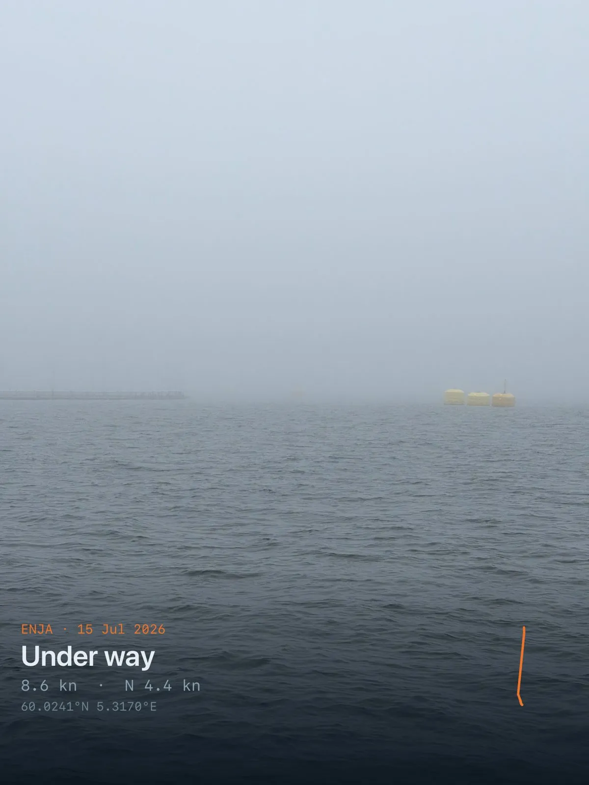 Flat grey water with no horizon; a faint yellow vessel just visible out to starboard in the fog
