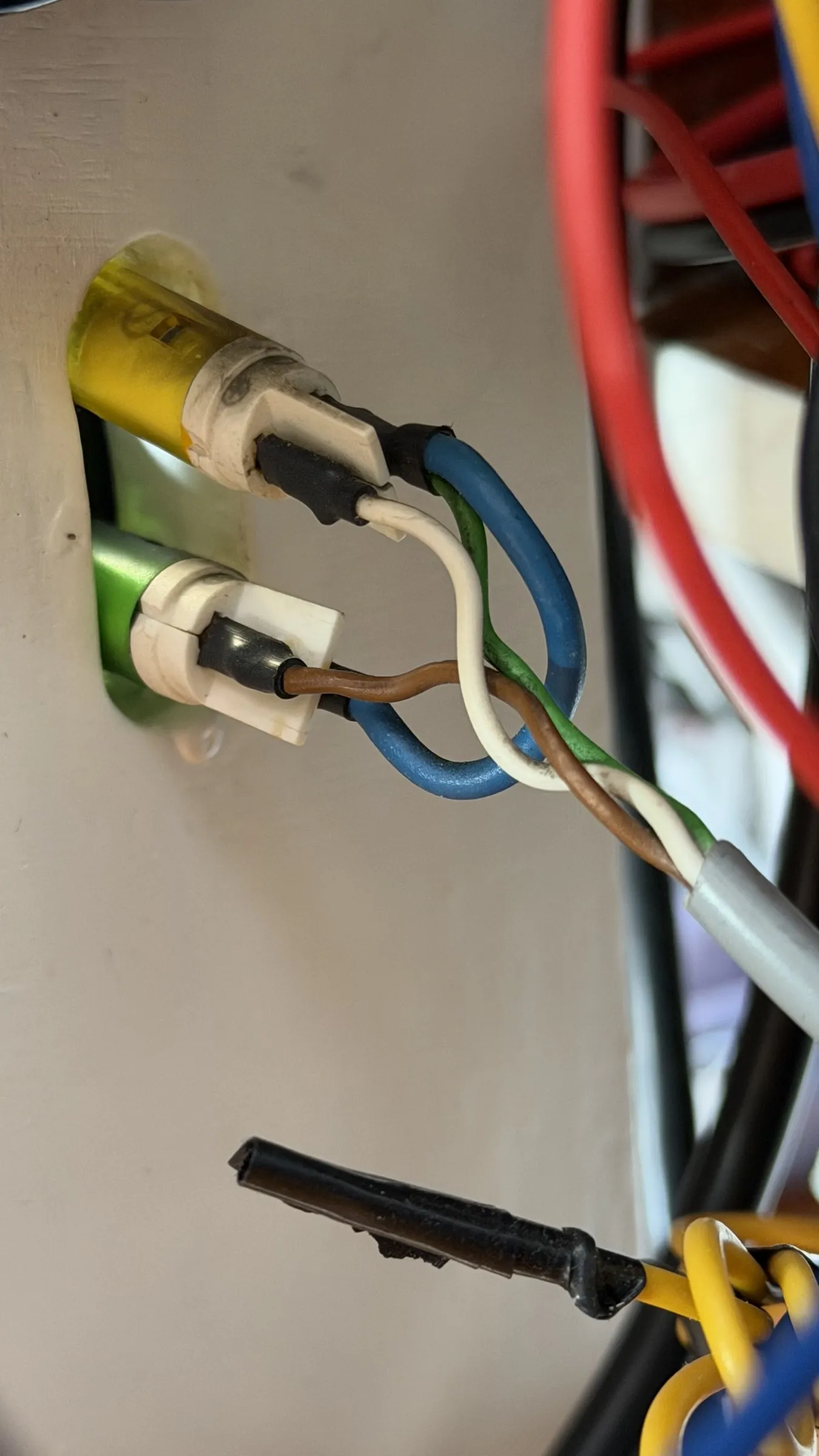 The backs of two panel lamps, one yellow and one green, with blue, white, brown and green wires looped between them