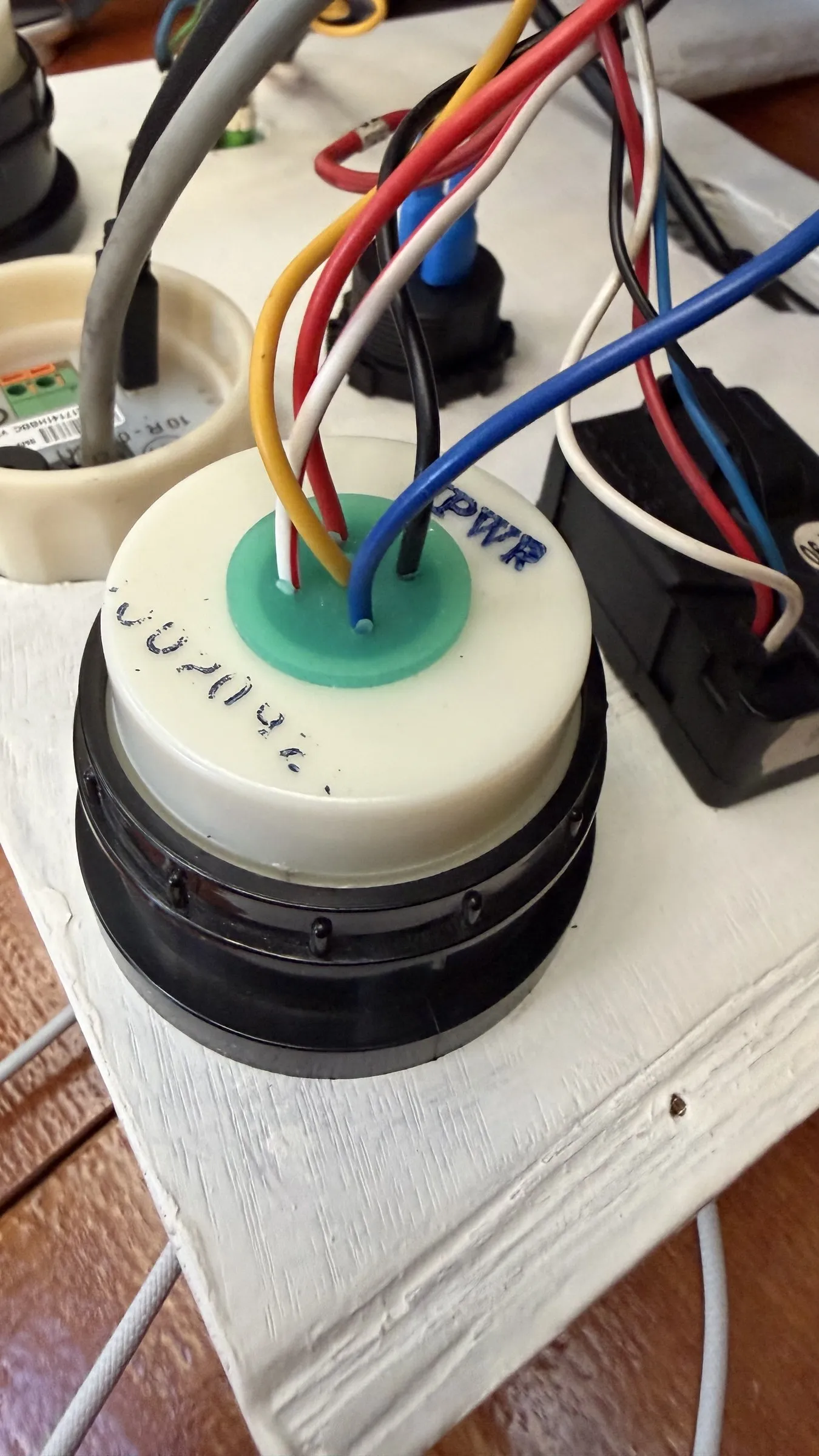 The top of a resistive tank sender, a white flange with a green seal and four coloured wires leaving it